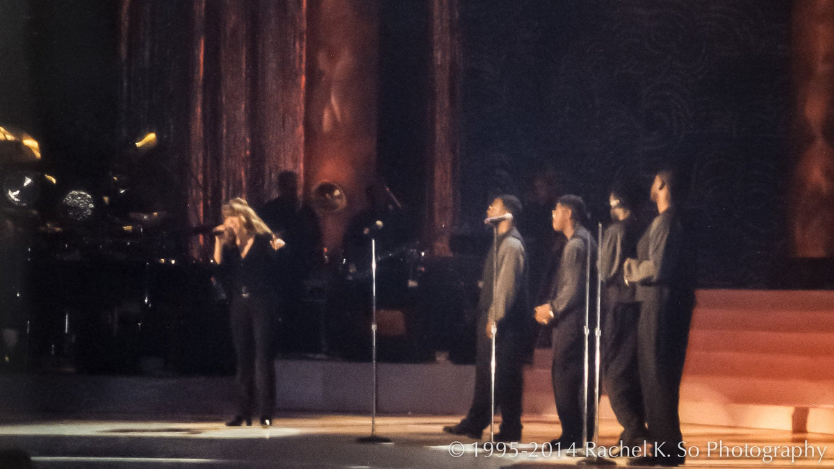 Mariah Carey performing live on stage with backing vocalists