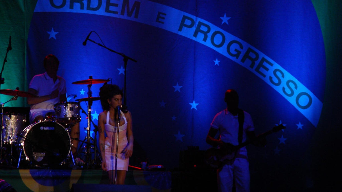 Amy Winehouse performing live on stage in Brazil in 2011, with her band, for the Black Parade vs Back to Black 20th anniversary vinyl buying guide